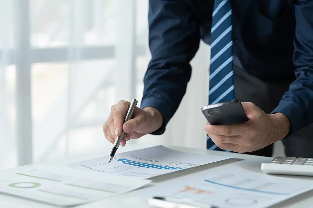 Business professional reviewing a report with bar charts while holding a smartphone