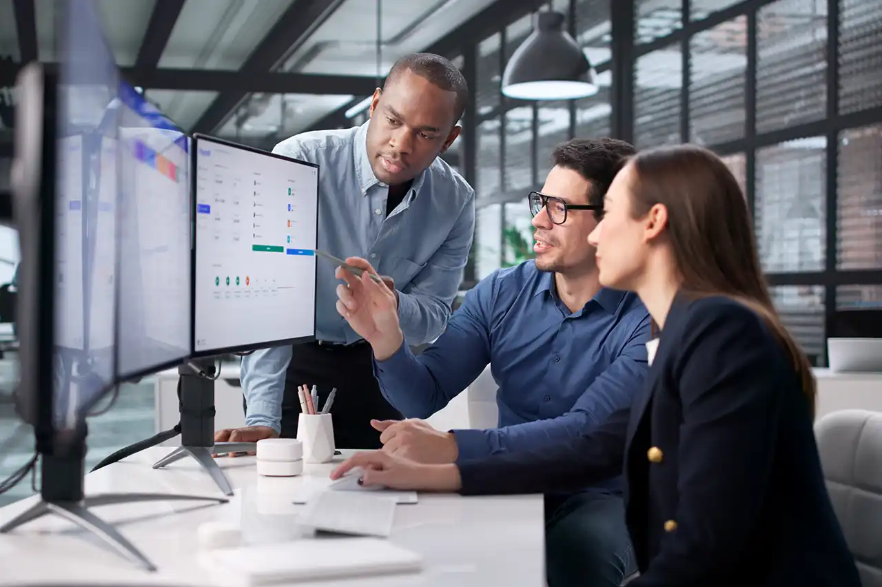 Team reviewing performance dashboards on multiple computer monitors in an office