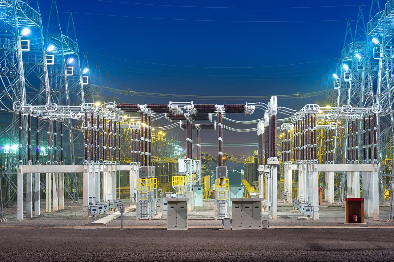 High-voltage substation at night with illuminated electrical equipment