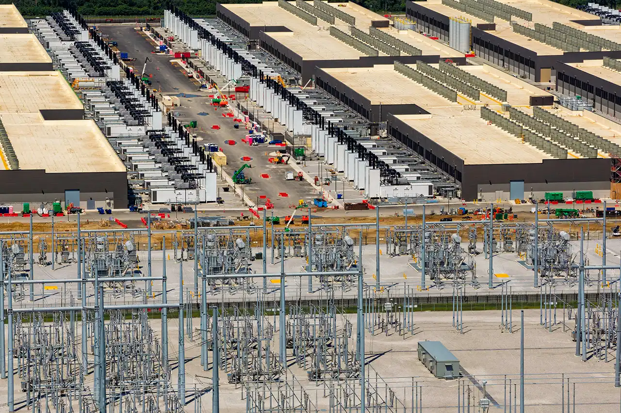Large industrial facility complex beside electric substation infrastructure